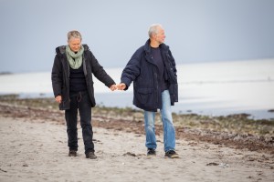 mature happy couple walking on beach in autumn lifestyle healthy